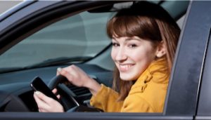 teen holding smartphone and driving